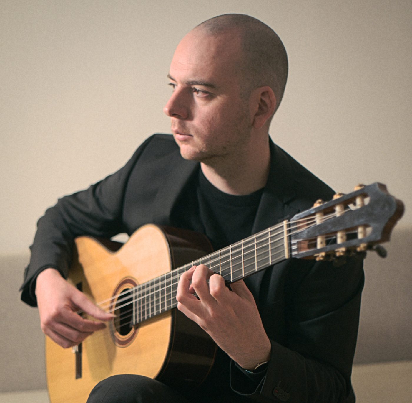 Tomás Peña playing classical guitar, looking to the side